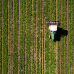 Drone shot of tractor cultivating agricultural field.