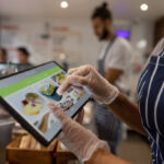 Close-up on a waitress using a tablet to take an order at a restaurant - food service concepts