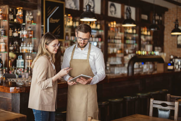 Male and female colleagues discussing plans while looking at a tablet standing in a coffee shop