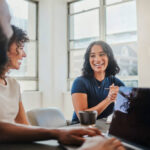 Business meeting, global company and teamwork diversity with laptop, black man and women in South African office. Smile, happy or creative people in communication, collaboration and strategy planning