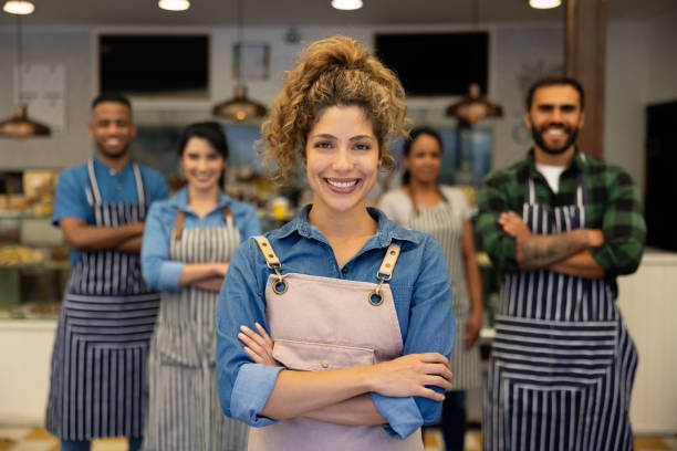 Group of wait staff looking happy working at a cafe and looking at the camera smiling - food service concepts
