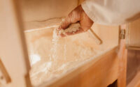 Man examining flour inside wooden grinding machine in mill