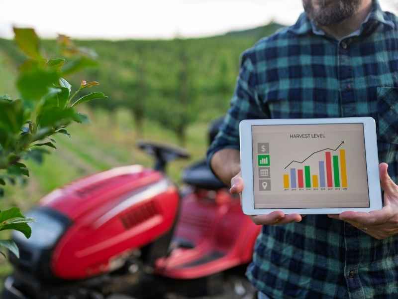 Farmer holding a tablet with harvest-level graphs, representing real-time data and digital tools used in AgriTech in Central America.