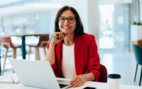 Business professional working on her laptop at an office desk, exuding confidence and focus. The image portrays professionalism in a bright environment.