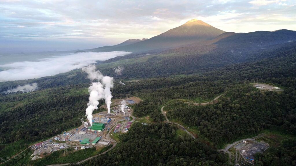Geothermal power plant with steam rising from industrial facilities, illustrating electricity generation using heat from beneath the Earth's surface.